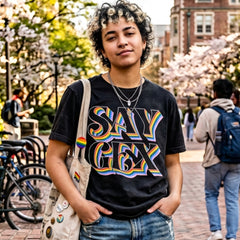 Young person wearing Say Gex funny rainbow meme t-shirt outdoors with pride tote bag and casual streetwear styling